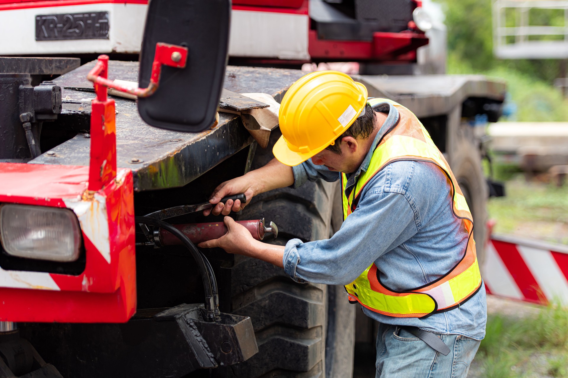 Engineers and technicians grease the wheel axle of a large crane before moving to the construction site