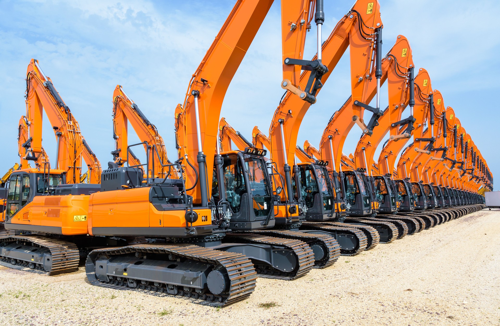 Row of excavators lined up outdoors.